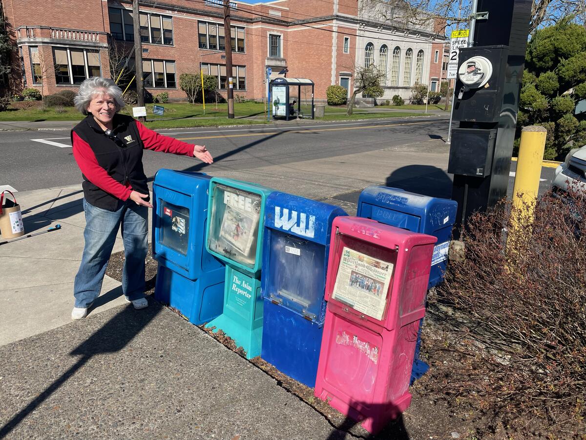 A volunteer with the newsletter distribution boxes on Fremont Street