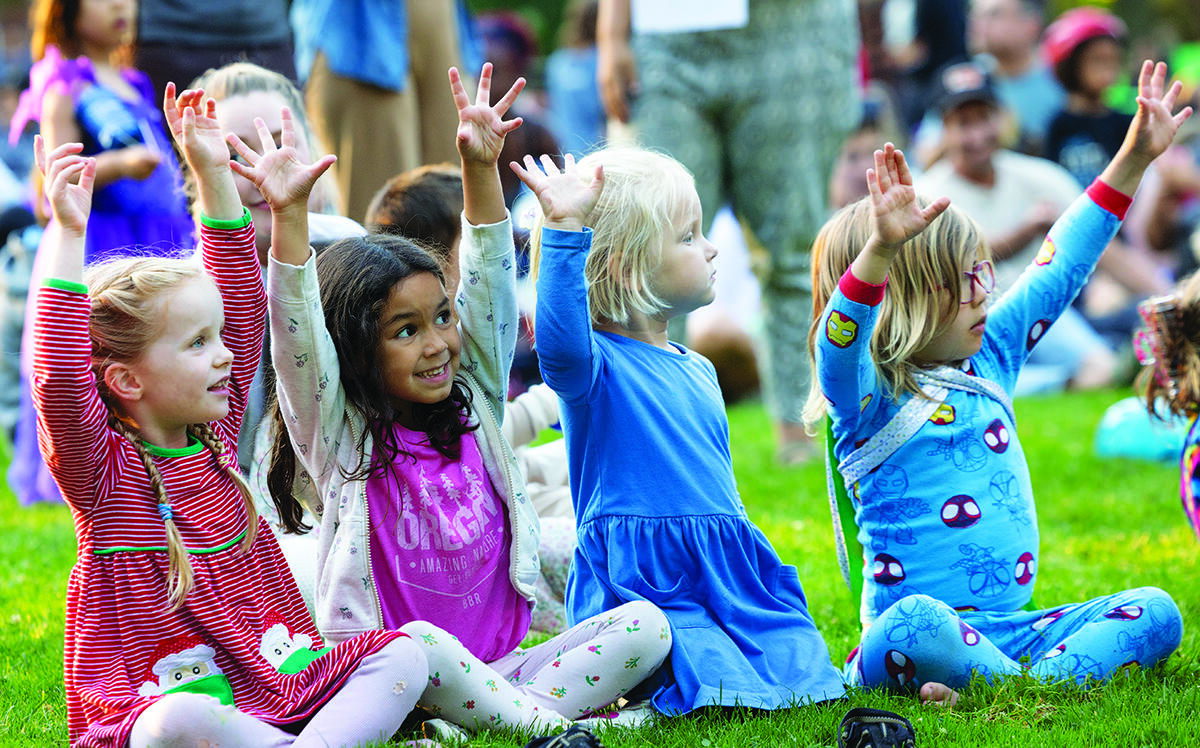 Kids raising their hands on the grass at a Movie in the Park event