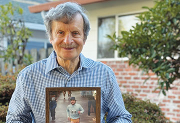 Ron Bockman showcases a photo of his first marathon in 1983. At 77 years old, he walks five miles every day in Beaumont-Wilshire. Photo by Jamie Gardner.