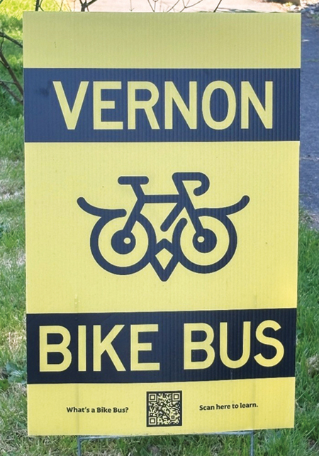 A 'Vernon Bike Bus' yard sign with a bicycle graphic and a QR code