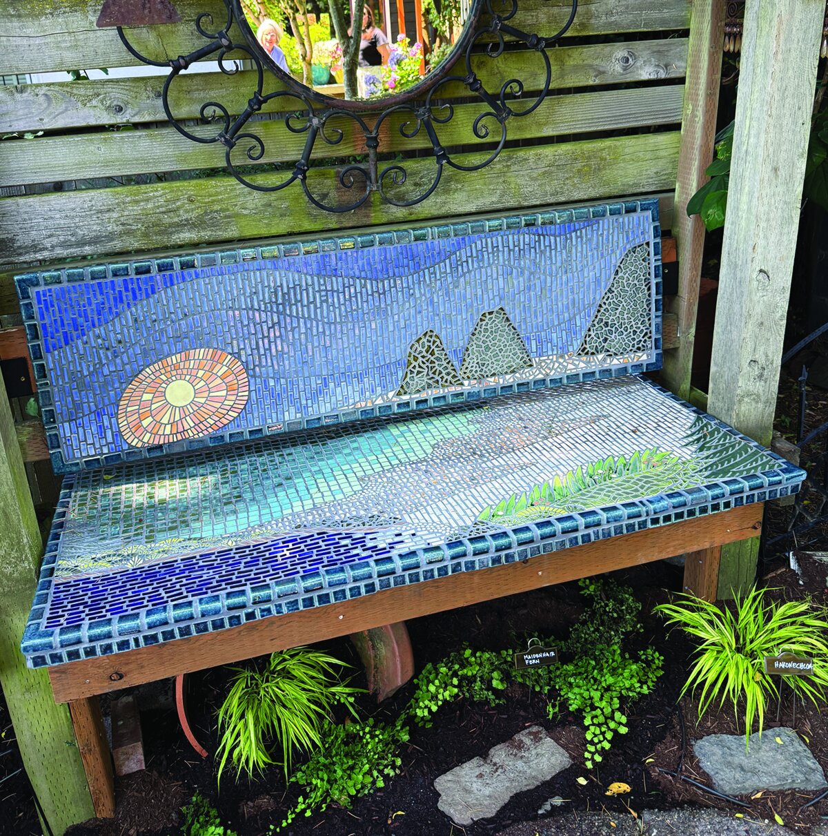 A garden bench decorated with a colorful mosaic.