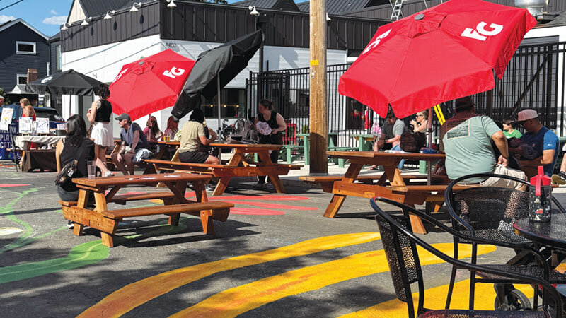 Picnic tables and umbrellas on the painted street surface of Beaumont Crossing.