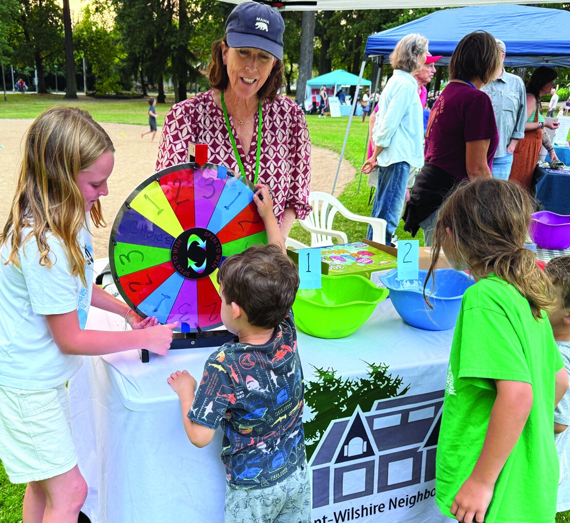 BWNA volunteer Ann Angulo helps kids with spinning-wheel game. Photo by Susan Trabucco.